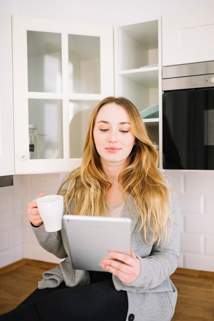 Free photo woman with tablet and drink in kitchen