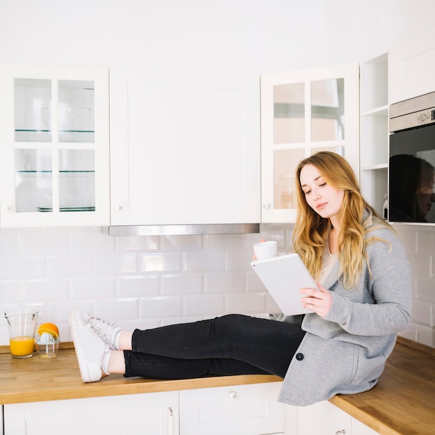 Free photo woman with tablet on kitchen counter