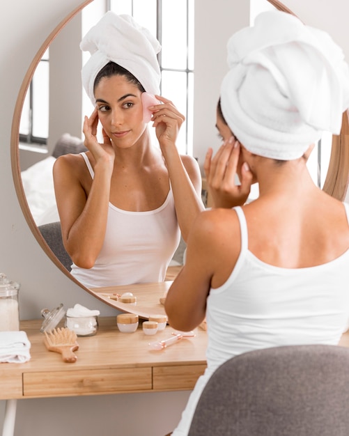 Free photo woman with towel looking into the mirror