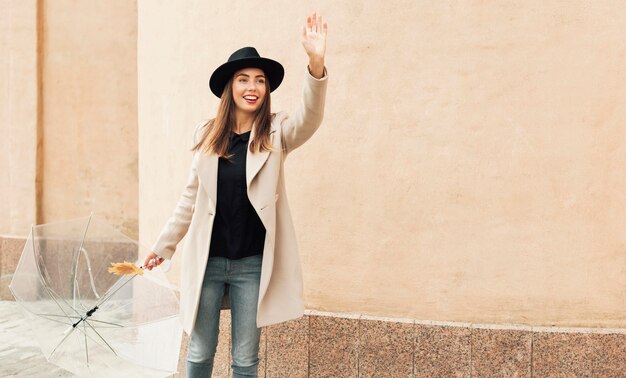 Woman with umbrella having her arm raised with copy space