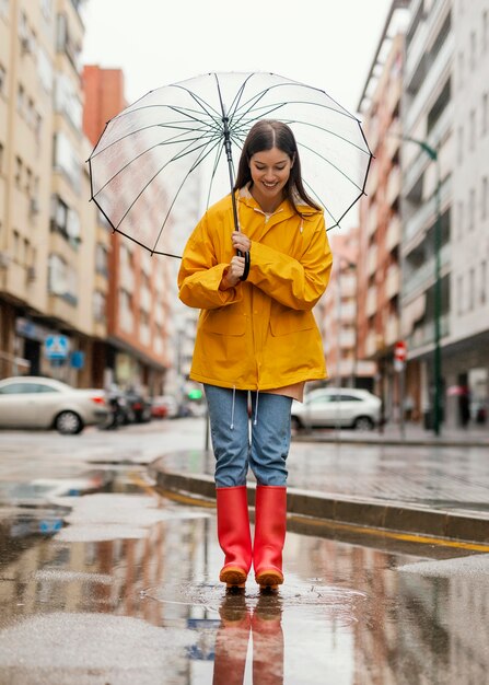 Woman with umbrella standing in the rain long view