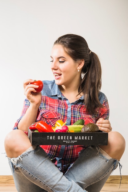 Woman with vegetables looking at tomato