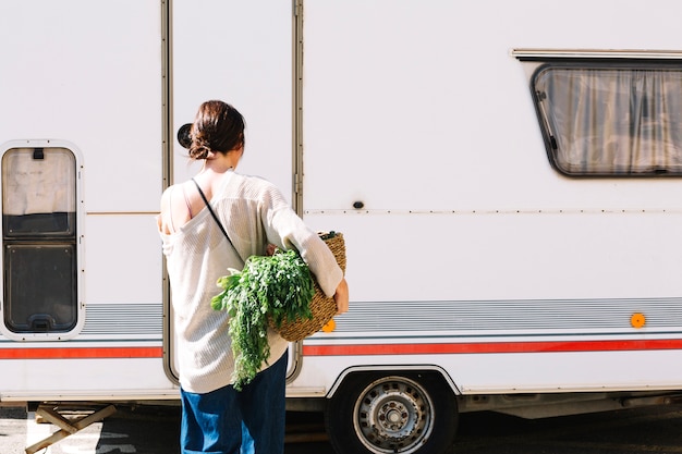 Free photo woman with vegetables near camper van