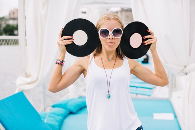 Free photo woman with vinyl records showing tongue