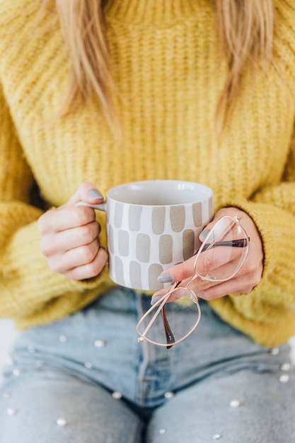 Free Photo woman with a warm cup of tea holding her eyeglasses