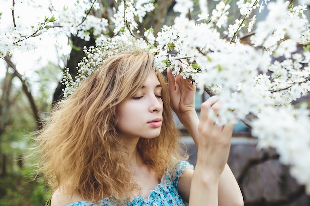 Woman with a wreath smelling flowering trees