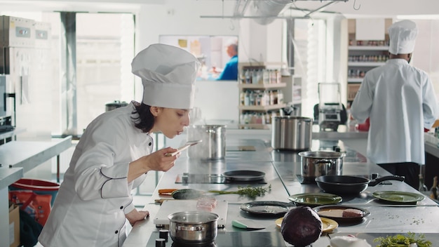 Free photo woman working as cook testing bad soup for gourmet dish, making mistake in preparing culinary recipe. authentic chef doing taste test with sauce, cooking in professional gastronomy kitchen.