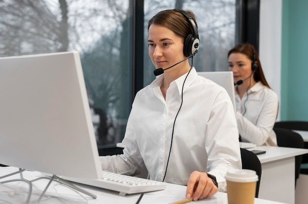 Woman working in call center office with headphones and computer