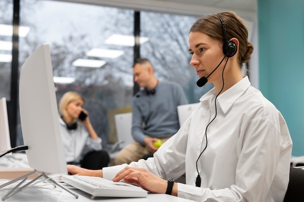 Woman working in a call center talking with clients using headphones and microphone