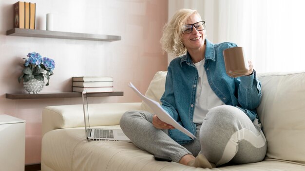 Woman working on couch and drinking coffee