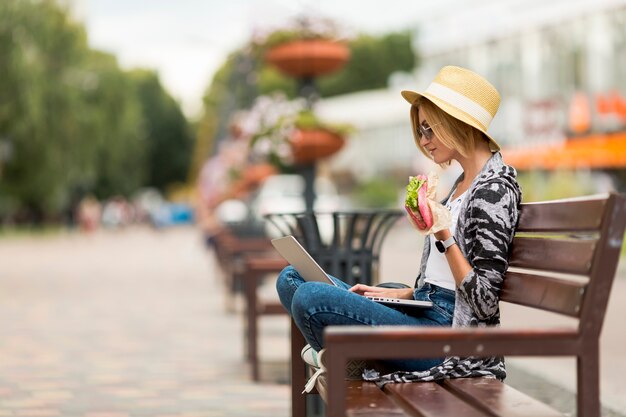 Woman working and eating on bench