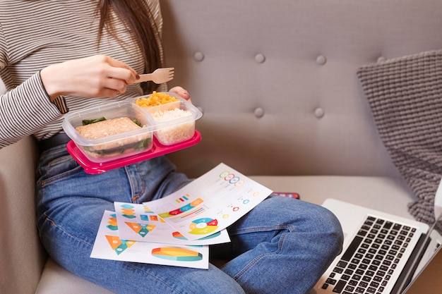 Woman working and eating on a sofa