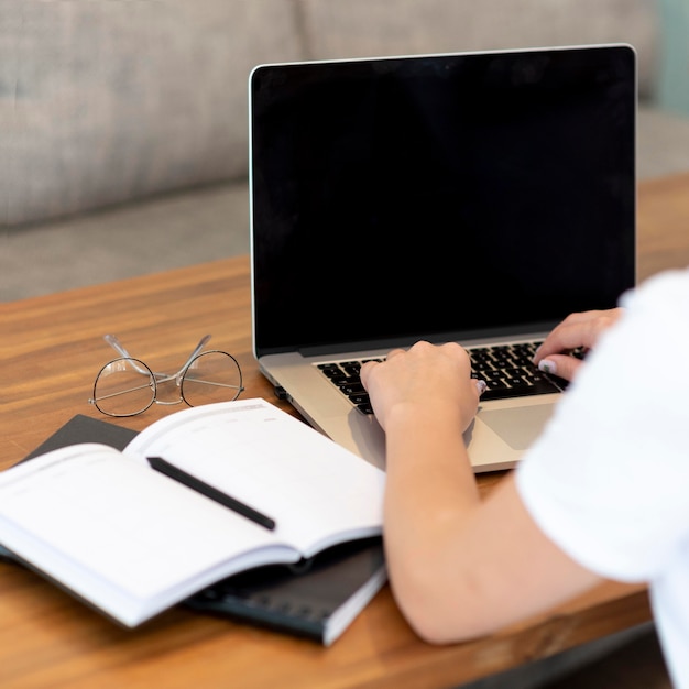 Woman working from home for social distancing with laptop and notebook