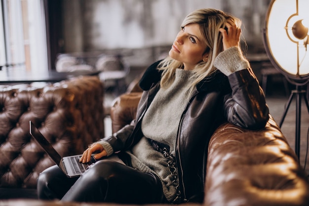 Free Photo woman working on laptop in a cafe and sitting coach