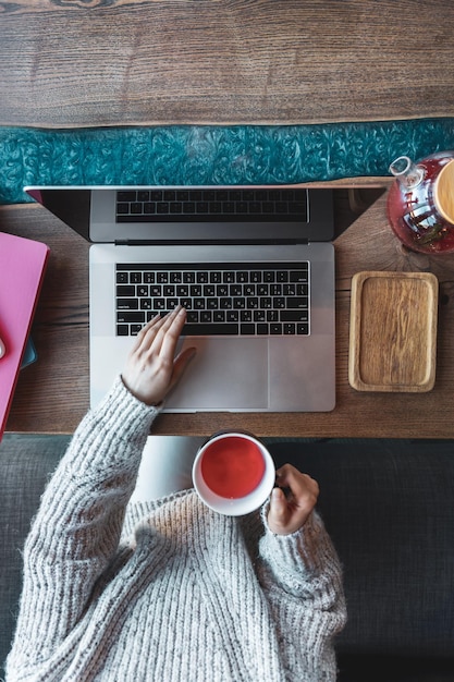 Free photo woman working on a laptop in a cafe with a cup of tea top view