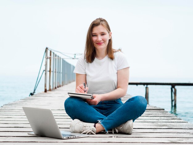 Woman working on laptop outside on pier