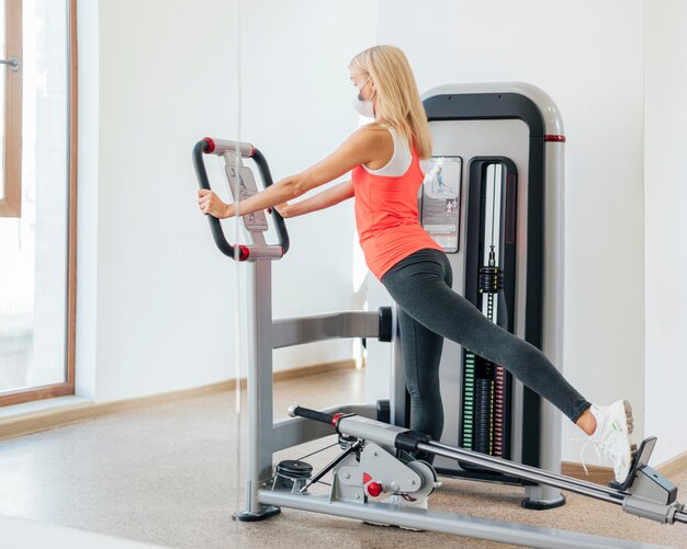 Woman working out at the gym with medical mask