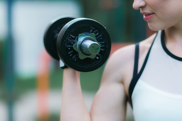 Free photo woman workout with dumbbell outdoor, biceps exercise closeup