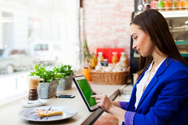 Woman works with a tablet at the table in a cafe