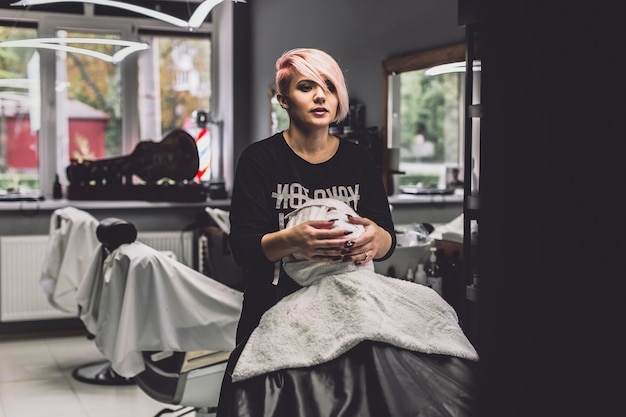 Woman wrapping face of client in barbershop