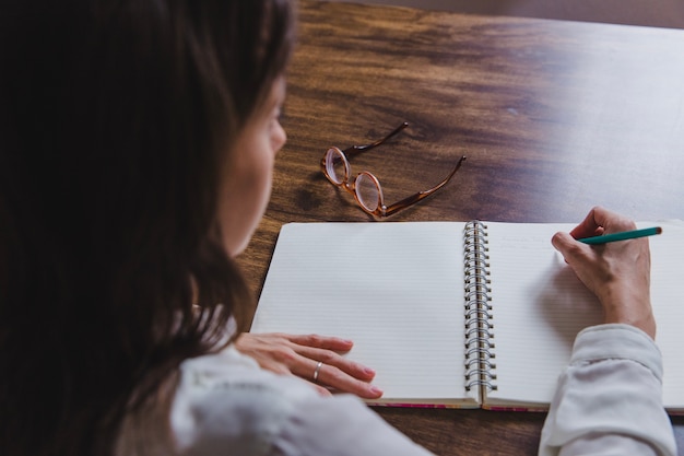 Woman writing in diary on wooden table