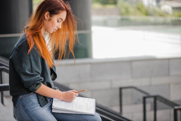 Woman writing on handrail