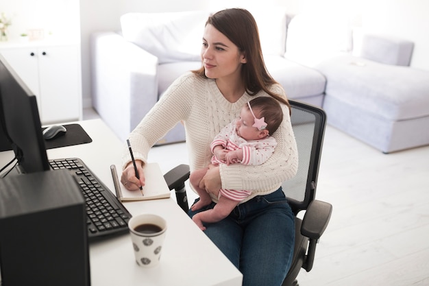 Woman writing and holding baby