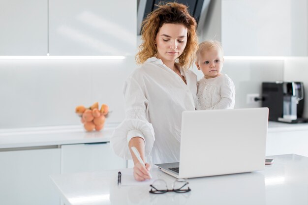 Woman writing holding baby