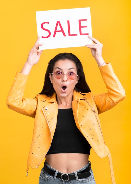 Woman in yellow jacket holding a sale banner