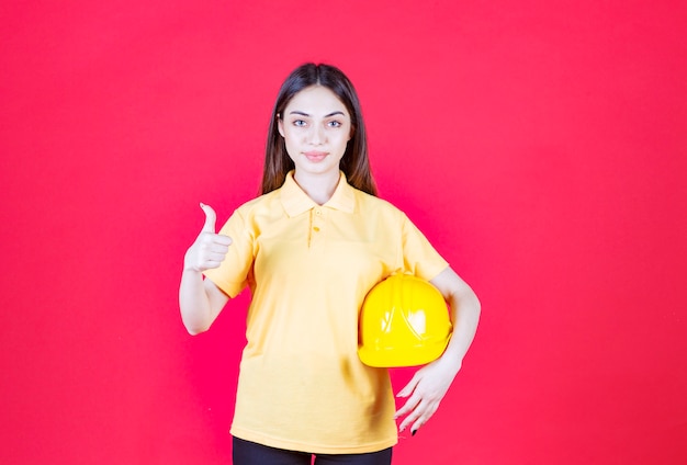 Free photo woman in yellow shirt holding a yellow helmet and enjoying the product.