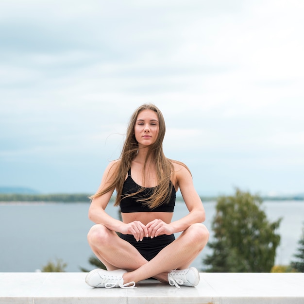 Free photo woman in yoga position looking at the camera long shot