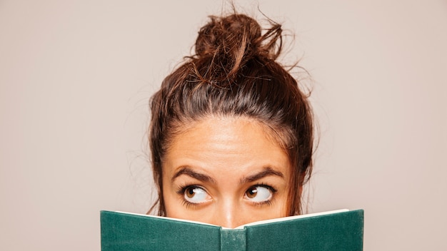 Free photo womans face behind a book