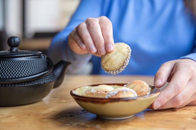 A womans hand takes a nutshaped cookie with condensed milk