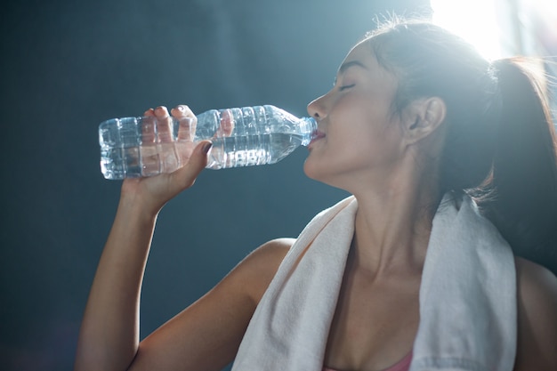 Free Photo women after exercise drink water from bottles and handkerchiefs in the gym.