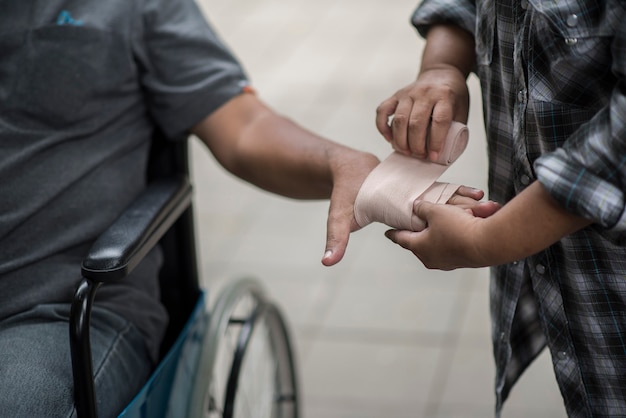 Free Photo women are wrapping hands on men sitting on wheelchair patients with bandages.