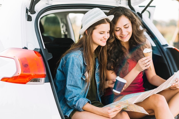 Women on car trunk with map