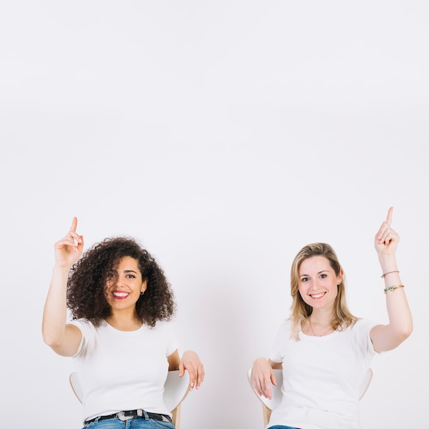 Free Photo women on chairs pointing up