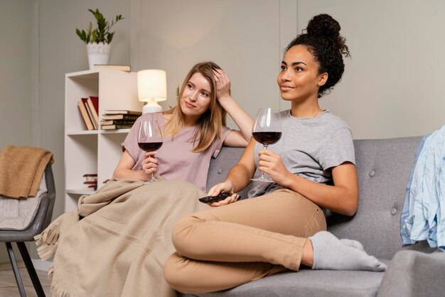 Women on couch watching tv and drinking wine