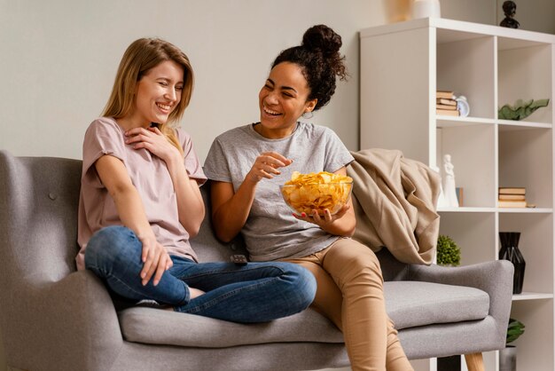 Women on couch watching tv and eating chips