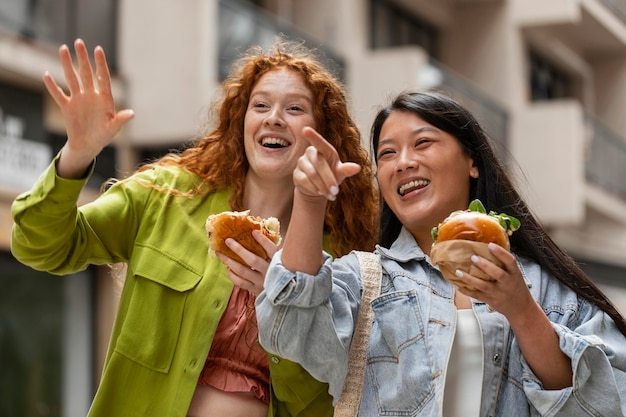 Free photo women eating delicious burgers outside