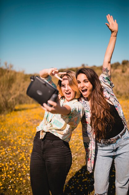 Women gesturing and taking selfie