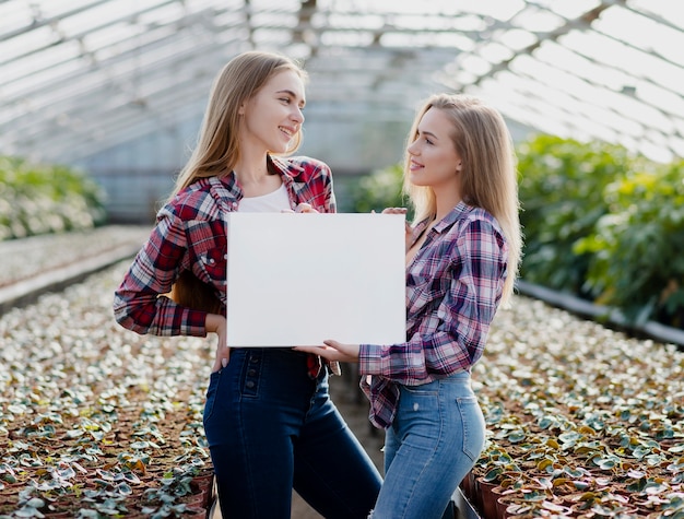 Women in greenhouse holding blank sheet