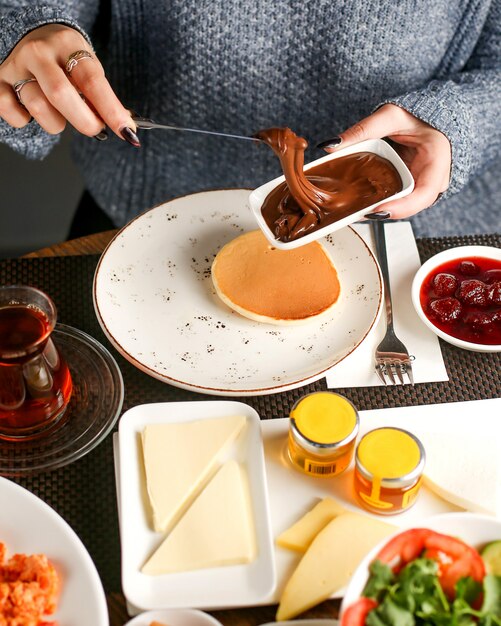 Women has breakfast with chocolate cream and pancake