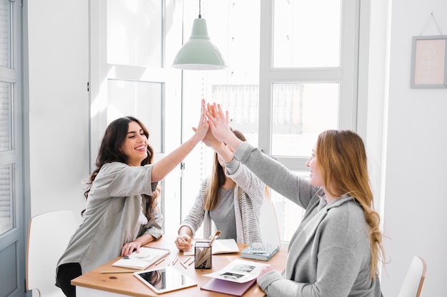 Free photo women high-fiving at table