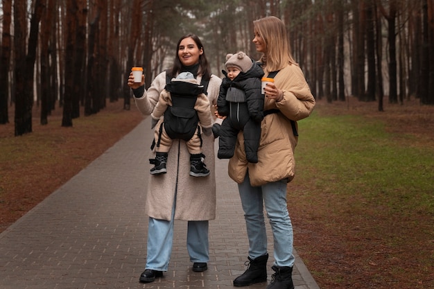 Free photo women holding babies in carriers full shot