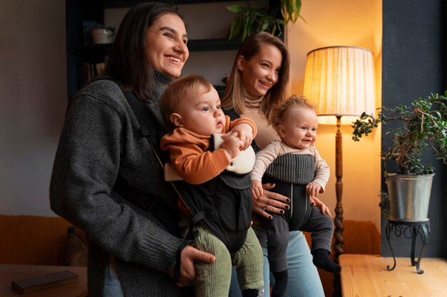 Women holding babies in carriers side view