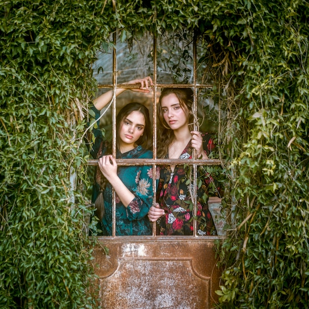 Free Photo women looking at camera through bars