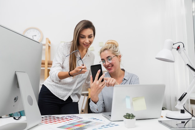 Women looking on phone at office