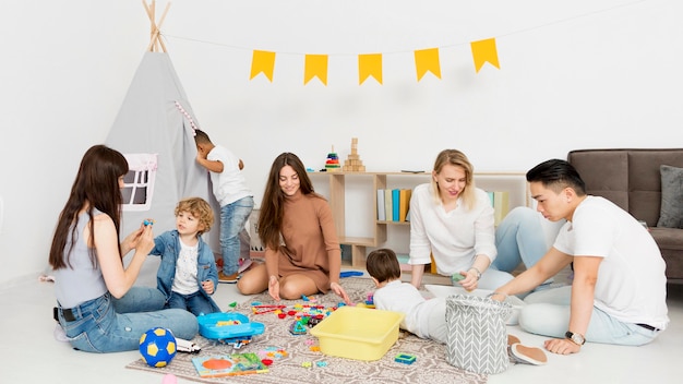 Women and man playing with children at home