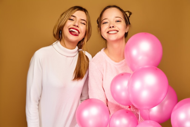 Free photo women models with pink air balloons on golden wall